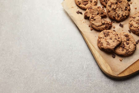 Many delicious chocolate chip cookies on gray table, top view. Space for text