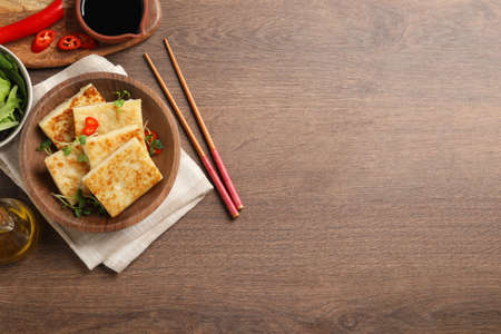 Delicious turnip cake with microgreens served on wooden table, flat lay. Space for textの写真素材
