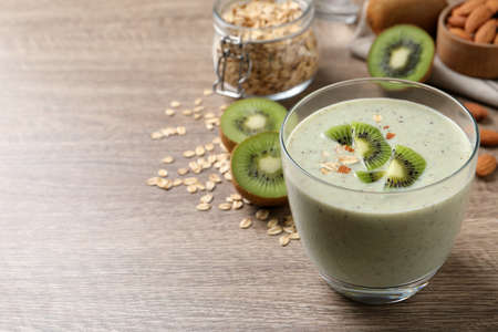 Glass of tasty kiwi smoothie with oatmeal on wooden table. Space for textの写真素材