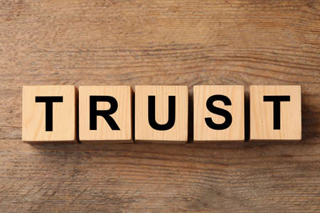 Cubes with word TRUST on wooden table, flat layの写真素材