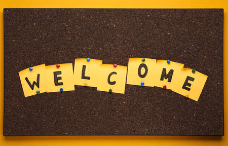 Corkboard with word Welcome made of paper notes on yellow background, top viewの写真素材