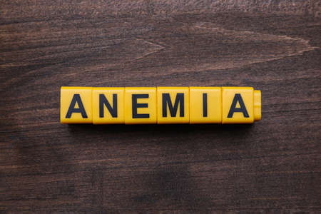 Word Anemia made with yellow cubes on wooden table, flat layの写真素材