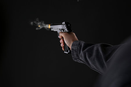 Man shooting from gun on black background, closeup