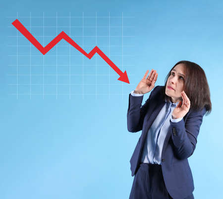 Worried businesswoman and illustration of falling down chart on light blue background. economy...
