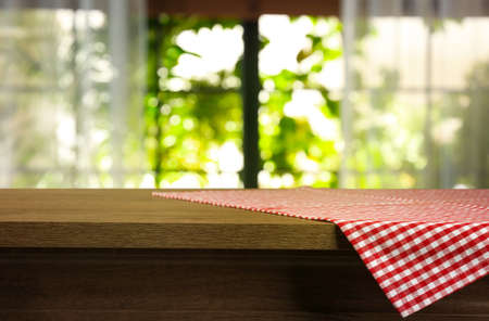 Red and white checkered tablecloth on wooden table indoors, space for design. bokeh effect