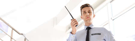 Male security guard with portable radio transmitter indoors. banner designの写真素材