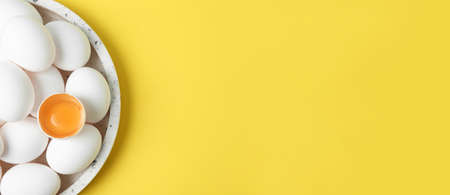 Plate with fresh raw chicken eggs on yellow background, top view with space for text. banner design