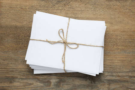Stack of letters tied with twine on wooden table, top view