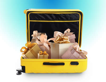 Beautiful gift boxes in yellow suitcase on color background