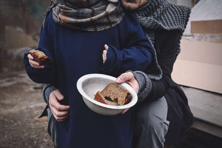 Poor father and child with bread at dump, closeupの写真素材