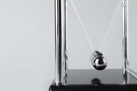 Newton's cradle on light background, closeup. Physics law of energy conservation