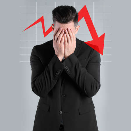 Upset businessman and illustration of falling down chart on light gray background. economy recession conceptの写真素材