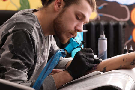 Professional artist making tattoo on hand in salonの写真素材