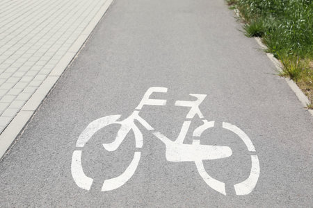 Bicycle lane with white sign painted on asphalt near sidewalk