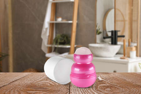 Roll-on deodorant on wooden table in bathroom