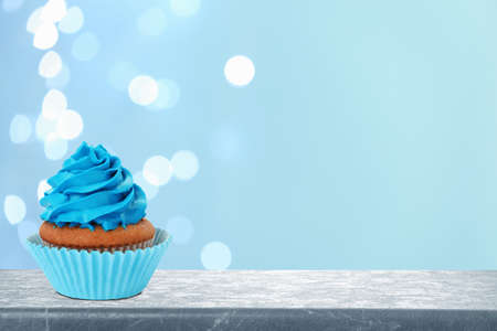 Delicious birthday cupcake on gray table against blurred lights. Space for textの写真素材