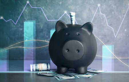 Black piggy bank with money on gray table. illustration of financial graphsの写真素材