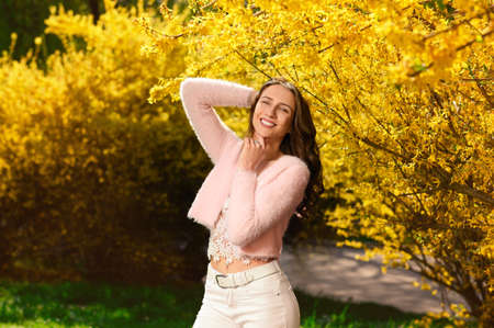 Beautiful young woman near blossoming shrub on spring dayの写真素材