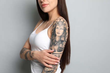 Beautiful woman with tattoos on arms against gray background, closeupの写真素材