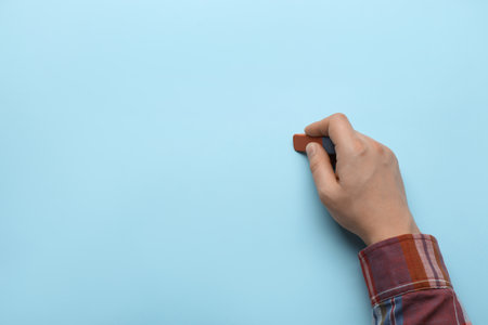 Man erasing something on light blue background, closeup. Space for textの写真素材