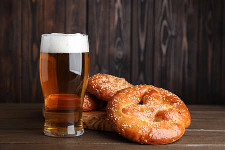 Tasty pretzels and glass of beer on wooden table