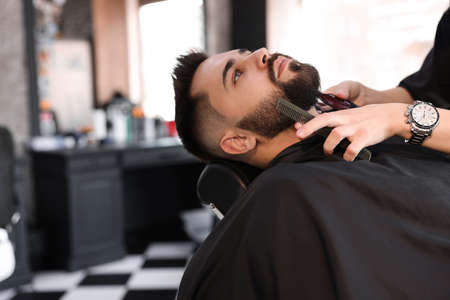 Professional hairdresser working with client in barbershopの写真素材