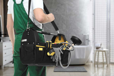 Plumber with bag of instruments in bathroom, closeup. Space for textの写真素材