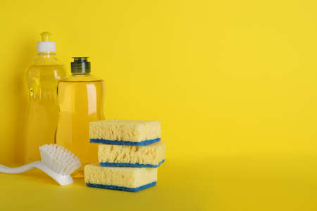 Sponges and other cleaning products on yellow background. Space for textの写真素材