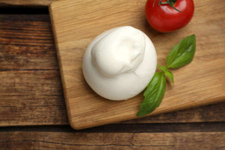 Delicious burrata cheese with basil and cherry tomato on wooden table, top viewの写真素材