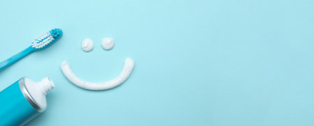 Smiling face made of toothpaste, brush and tube on light blue background, flat lay with space for text. banner designの写真素材
