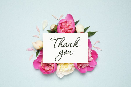 Beautiful peonies and card with phrase Thank You on light blue background, flat layの写真素材