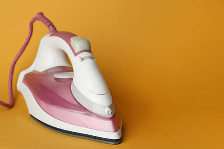 One modern iron on orange background, space for text. home appliancesの写真素材