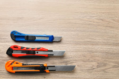 Different utility knives on wooden table, flat lay. Space for textの写真素材