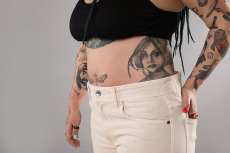 Woman with tattoos on body against gray background, closeupの写真素材