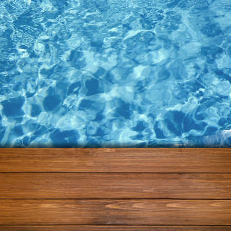 Empty blue wooden surface near swimming pool with clear water. space for design
