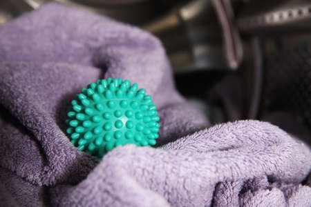 Green dryer ball and towel in washing machine drum, closeup. Space for textの写真素材