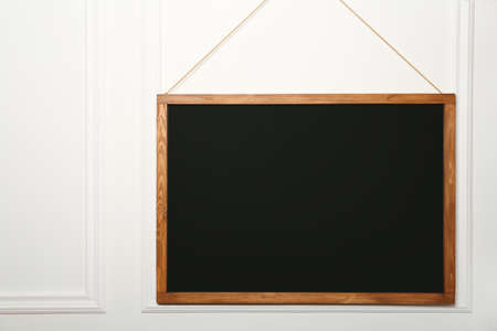 Clean black chalkboard hanging on white wall