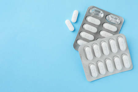 Blister packs with calcium supplement pills on light blue background, flat lay. Space for text