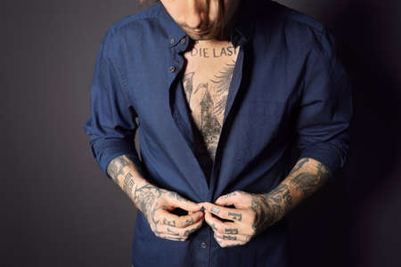 Young man with tattoos on body against black background, closeupの写真素材