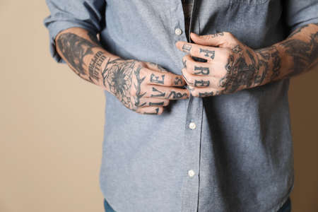 Young man with tattoos on body against beige background, closeupの写真素材