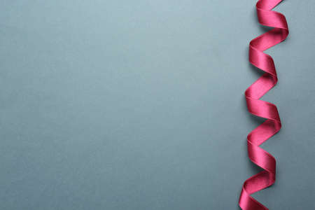 Beautiful pink ribbon on gray background, top view. Space for text