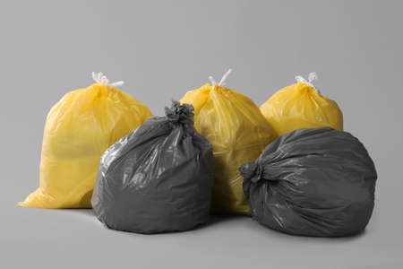 Trash bags full of garbage on gray background