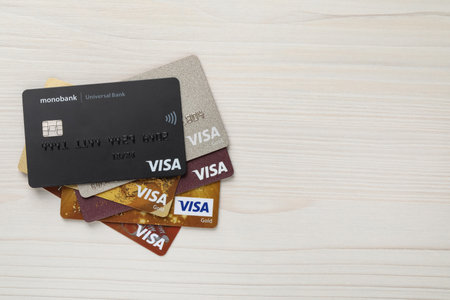 MYKOLAIV, UKRAINE - FEBRUARY 22, 2022: Visa credit cards on white wooden table, flat lay. Space for...