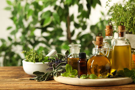 Different fresh herbs with oils on wooden tableの写真素材
