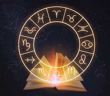 Open book, illustration of zodiac wheel with astrological signs and starry sky at nightの写真素材