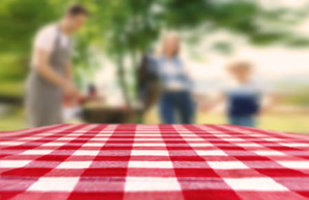 Table with checkered picnic cloth outdoors on sunny day. space for designの写真素材