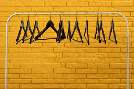 Wardrobe rack with many hangers near yellow brick wallの写真素材
