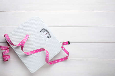 Bathroom scale, measuring tape and space for text on white wooden floor, top view. weight loss conceptの写真素材