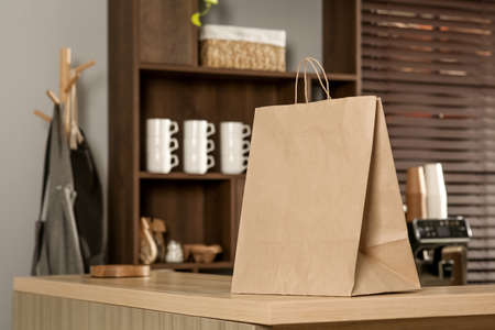 Paper bag on wooden counter in cafe, space for textの写真素材