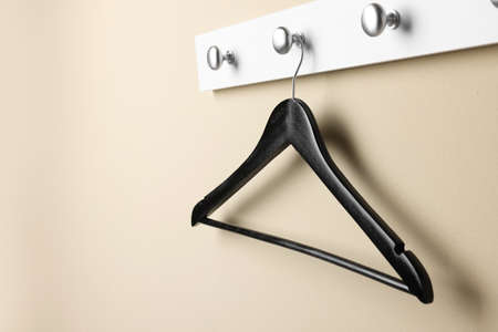 Rack with empty black clothes hanger on beige wall. Space for textの写真素材